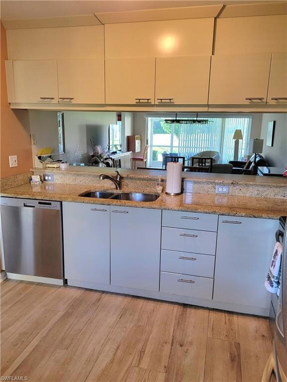 Kitchen featuring stainless steel appliances, light stone counters, and light wood-type flooring