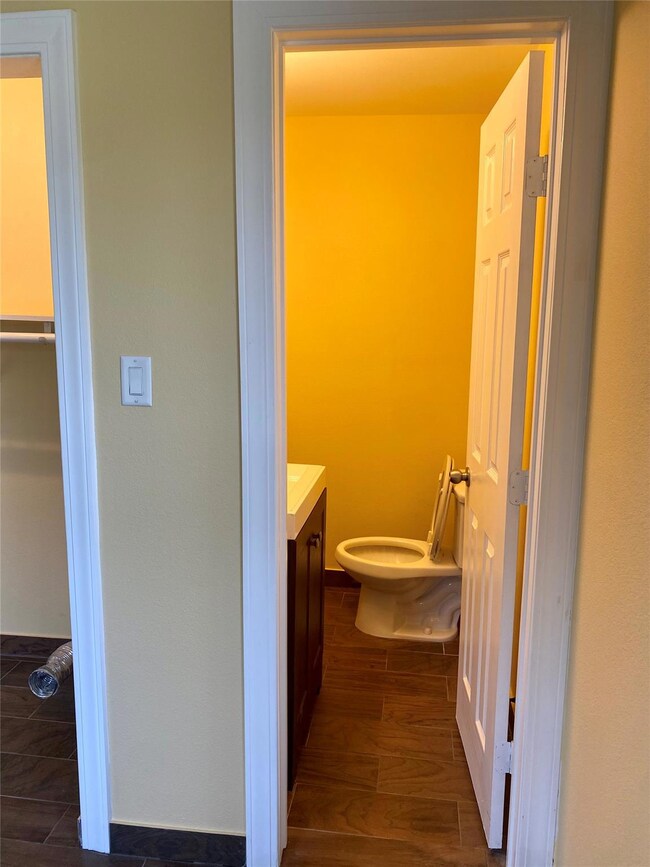 Bathroom with vanity, wood finished floors, and t