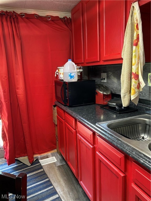 Kitchen featuring dark countertops, wood-type flooring, and brown cabinets
