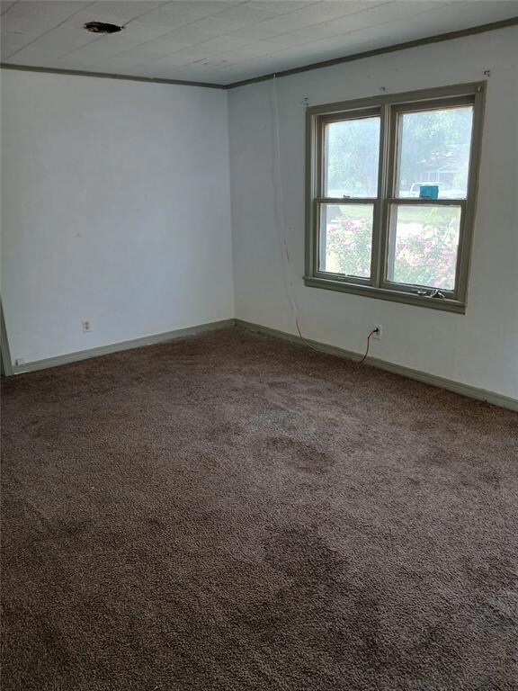 Carpeted spare room featuring baseboards