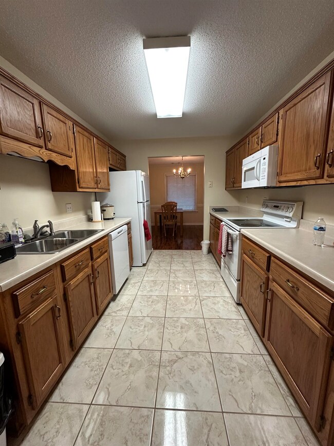 Kitchen featuring sink, white appliances, hanging 