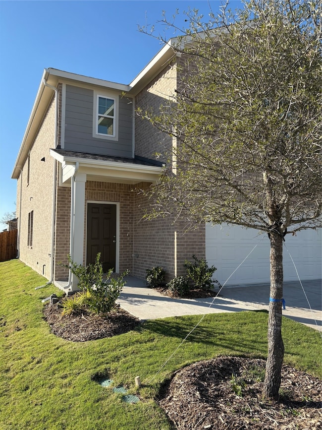 Traditional home featuring brick siding, a front lawn, a garage, and concrete driveway