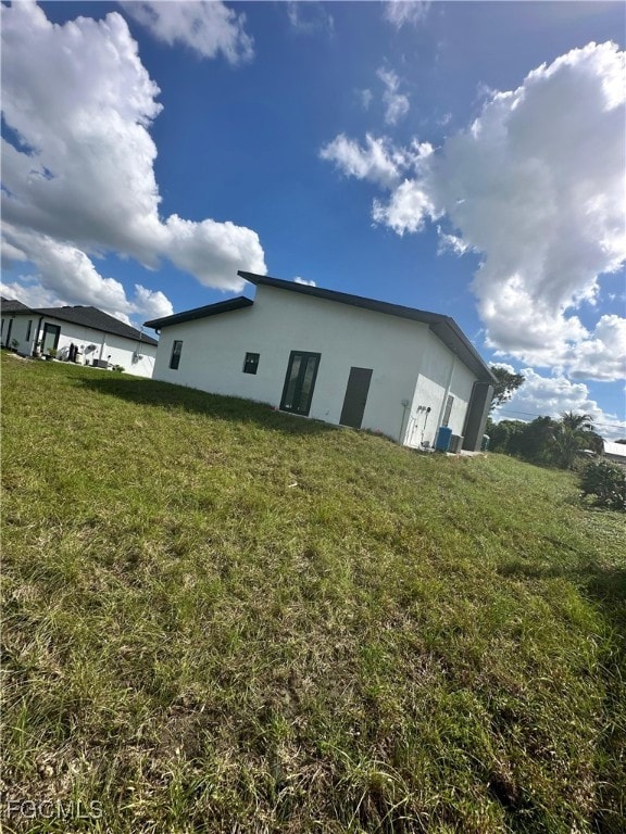 Rear view of property featuring stucco siding and a lawn