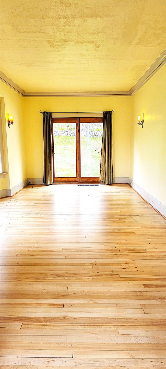 Spare room featuring ornamental molding, hardwood / wood-style floors, and baseboards