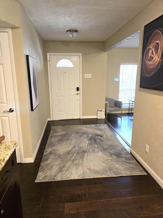 Foyer entrance with baseboards, a textured ceiling