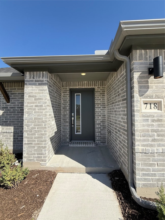Property entrance featuring brick siding and a porch