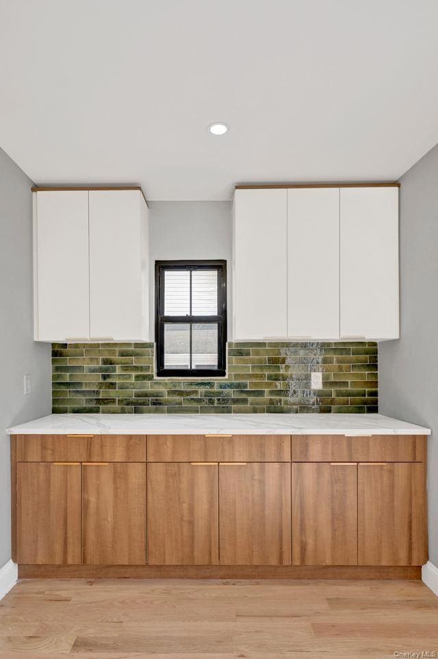 Kitchen with modern cabinets, brown cabinetry, white cabinetry, light wood finished floors, and recessed lighting