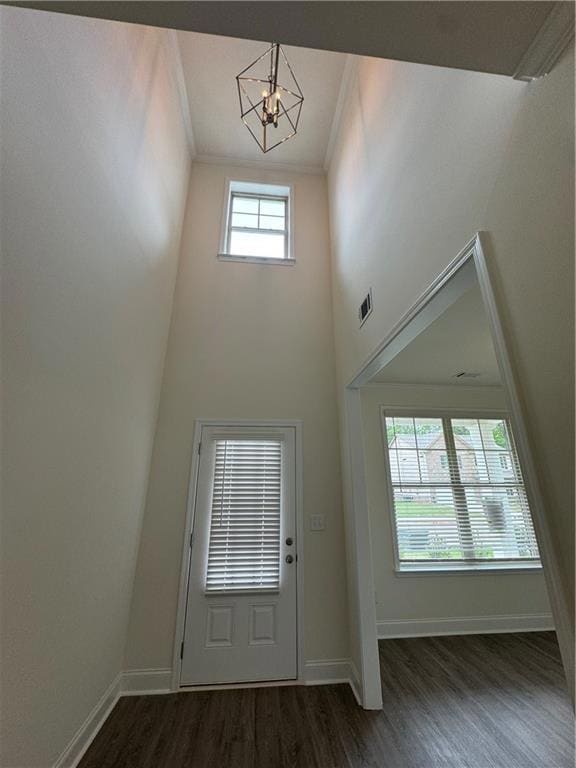 Entrance foyer with ornamental molding, a chandelier, dark wood finished floors, and a high ceiling