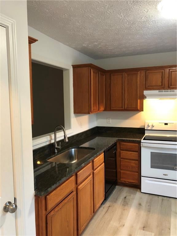 Kitchen with stove, extractor fan, dishwasher, a sink, and light wood-type flooring