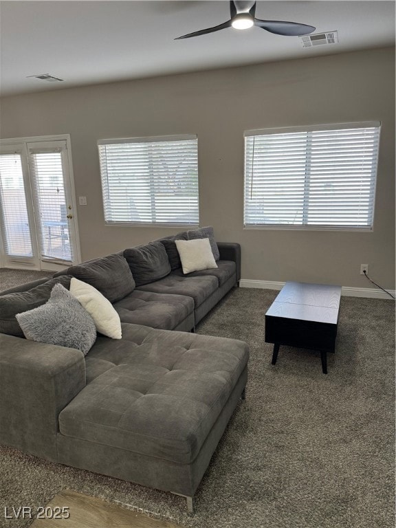 Carpeted living area featuring a ceiling fan, plen