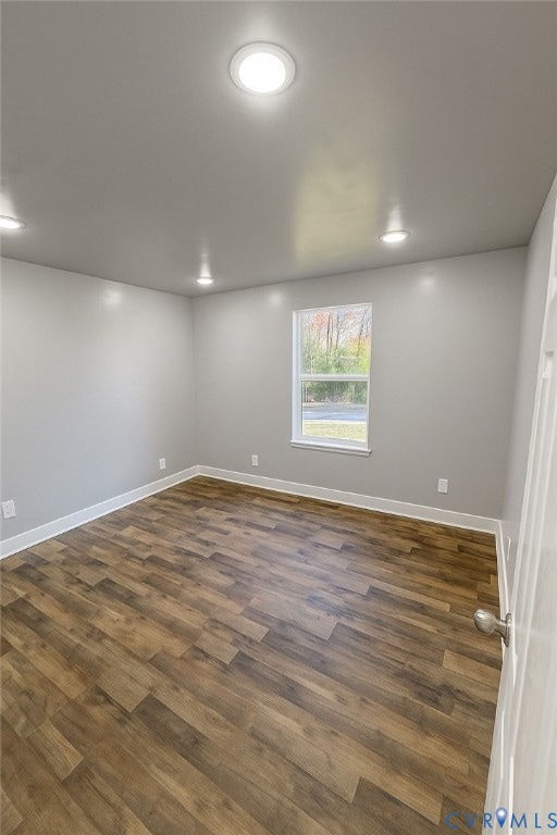 Empty room with dark wood-type flooring and recessed lighting