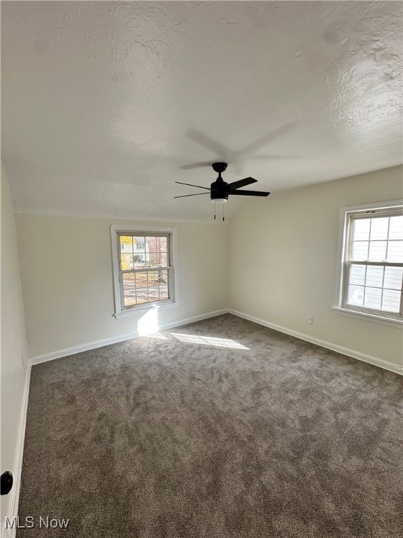 Unfurnished room with dark carpet, a textured ceiling, and ceiling fan