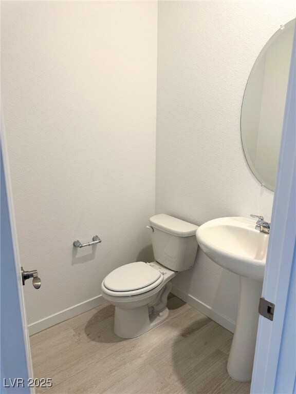 Bathroom with wood finished floors, toilet, and ba