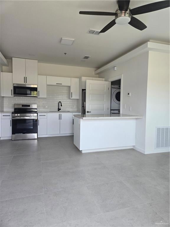 Kitchen with range, a sink, white cabinets, light countertops, and tasteful backsplash