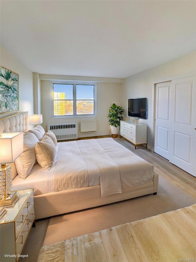 Bedroom with radiator heating unit, wood finished floors, and a closet
