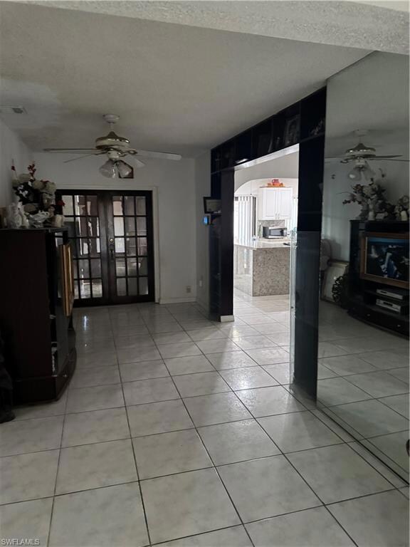 Unfurnished living room featuring light tile patterned flooring, ceiling fan, arched walkways, a textured ceiling, and visible vents