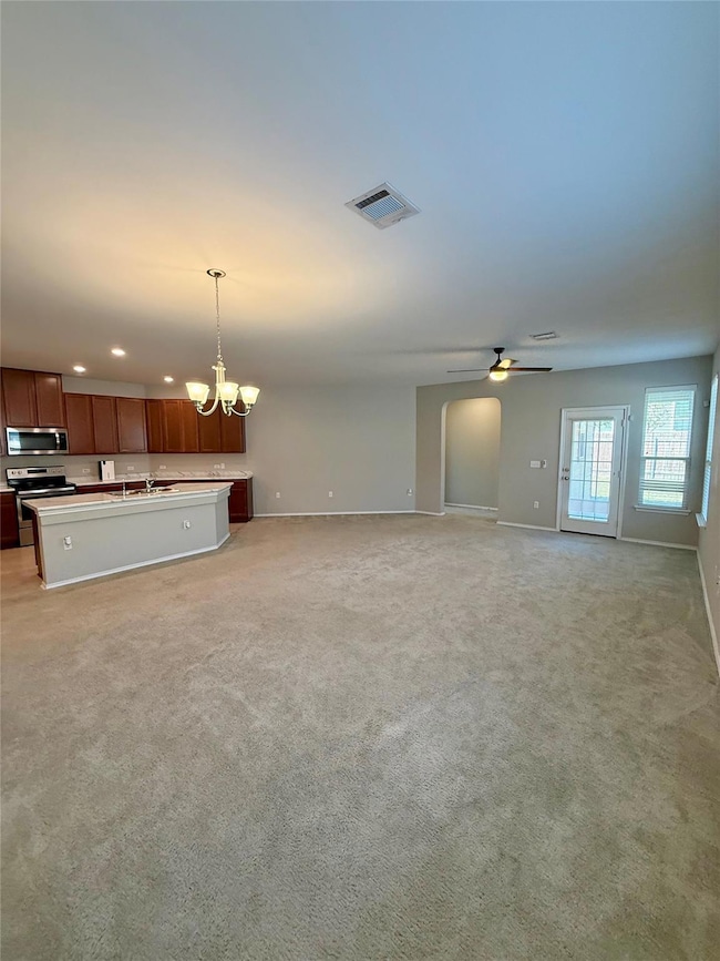 Unfurnished living room with a chandelier, light colored carpet, a ceiling fan, and recessed lighting