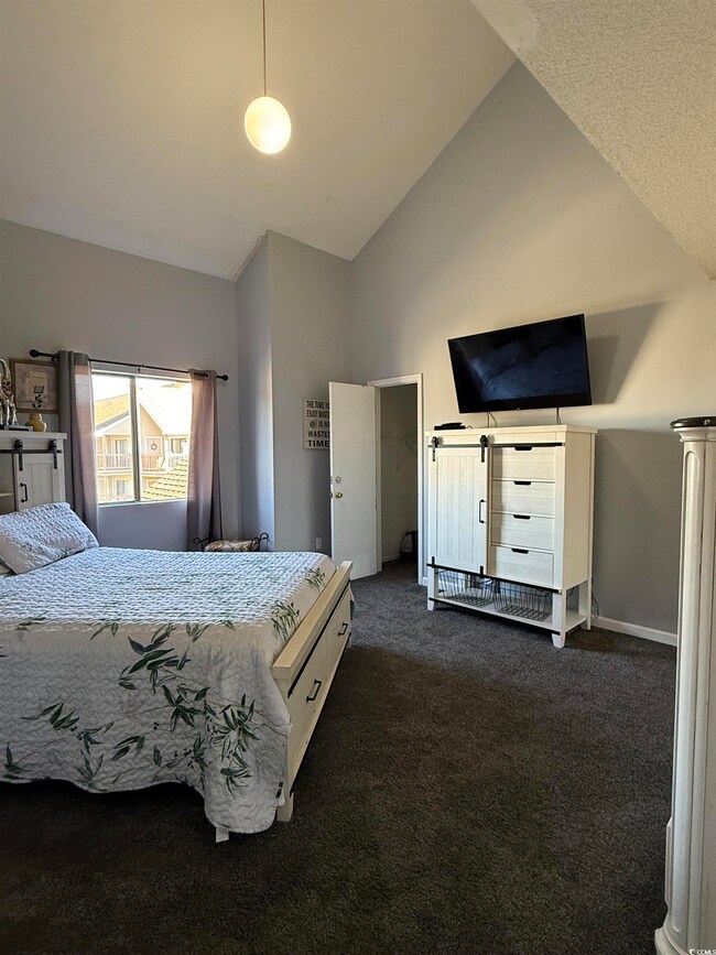Bedroom with dark carpet and high vaulted ceiling