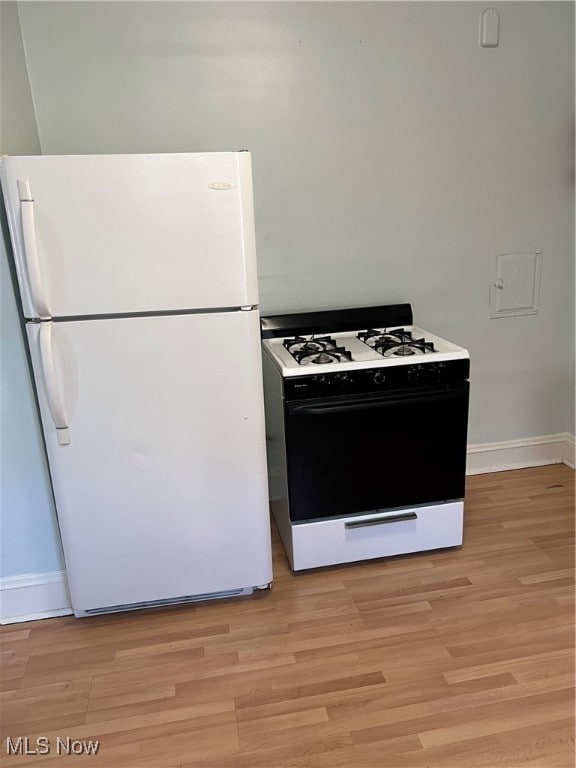Kitchen with gas stove, white fridge, and light wood-type flooring