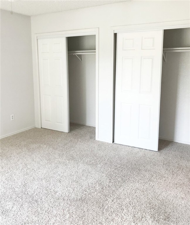 Unfurnished bedroom featuring two closets and carpet floors