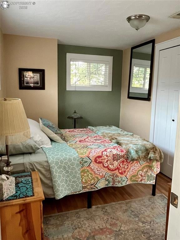 Bedroom with wood finished floors and a closet