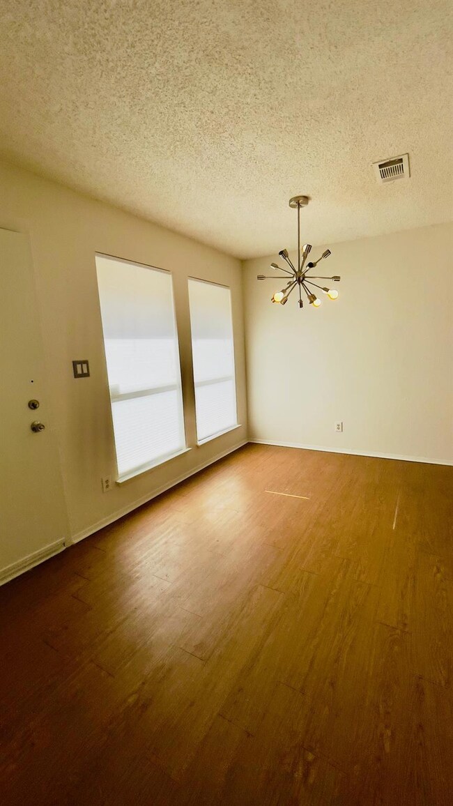 Empty room with a textured ceiling, baseboards, v