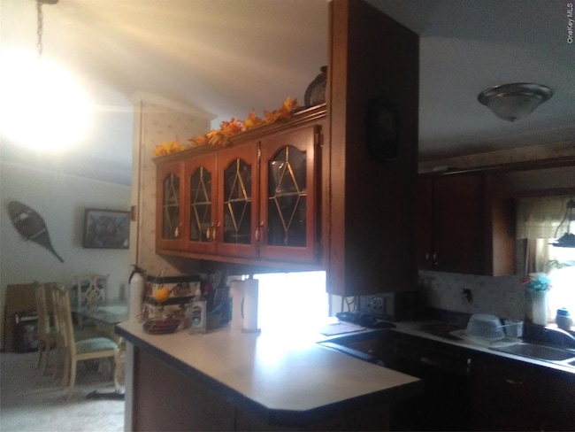 Kitchen featuring glass insert cabinets, a peninsula, and light countertops
