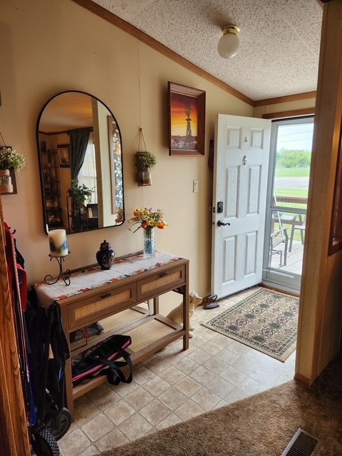 Entrance foyer with a textured ceiling, crown molding, and light colored carpet