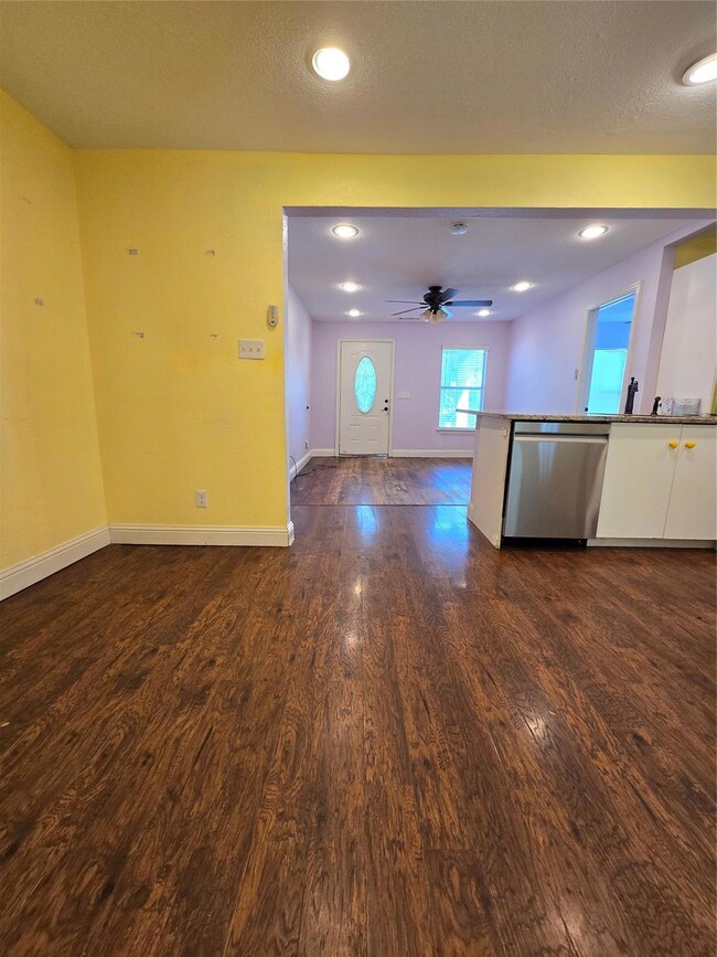 Unfurnished living room with ceiling fan and hardw