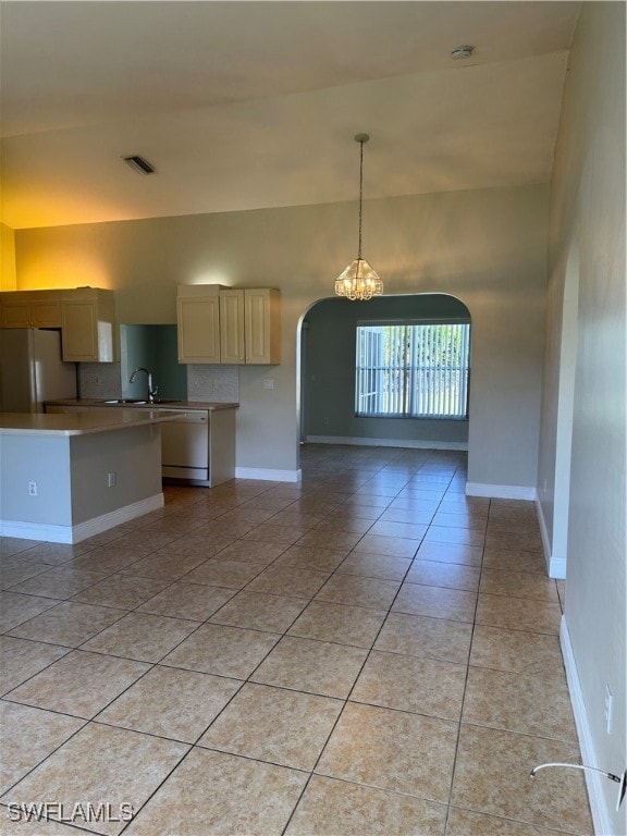 Kitchen with sink, dishwasher, refrigerator, light tile patterned floors, and a chandelier