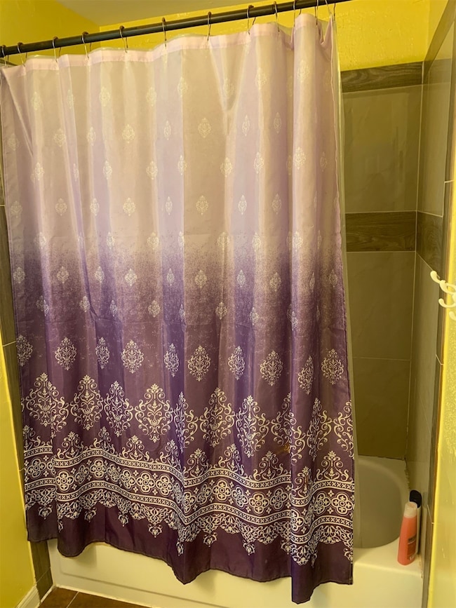 The photo shows a bathroom with a purple shower cu