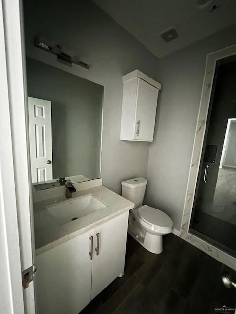 Bathroom with walk in shower, vanity, toilet, and hardwood / wood-style flooring