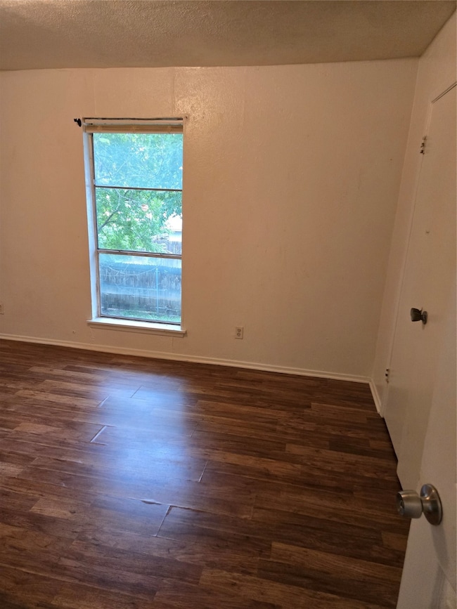 Unfurnished room featuring dark wood-type flooring and a textured ceiling
