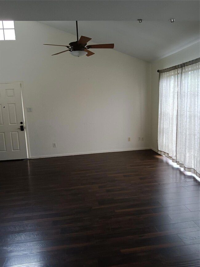 Unfurnished room featuring a ceiling fan, dark woo