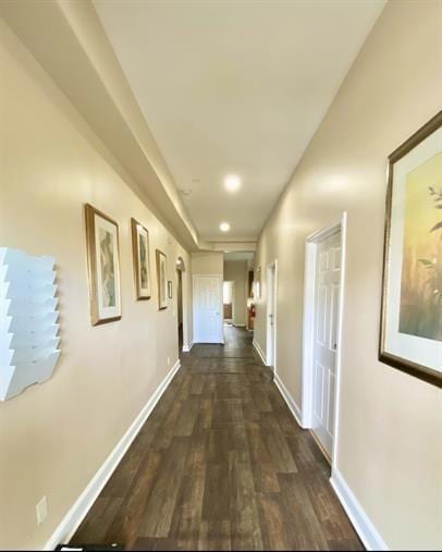 Corridor featuring dark wood-style floors and baseboards