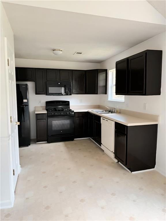 Kitchen with appliances, dark cabinets, light countertops, and light floors
