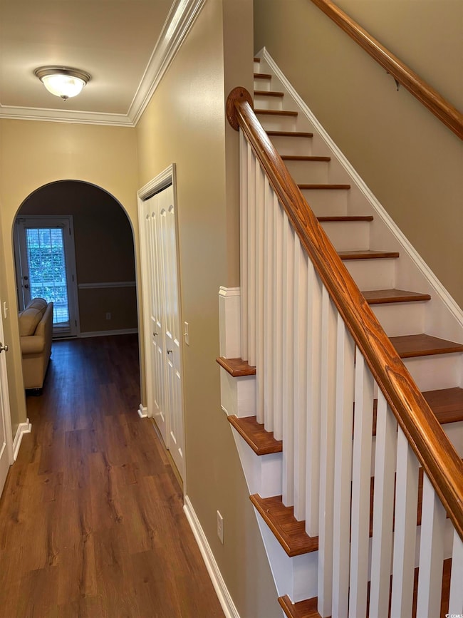 Staircase with crown molding and wood-type floorin