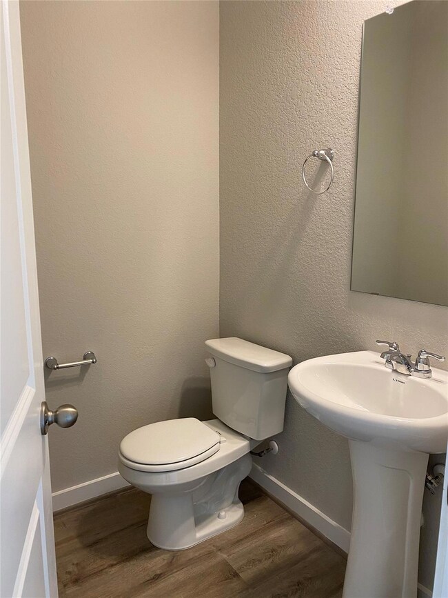 Bathroom with wood finished floors, toilet, baseb