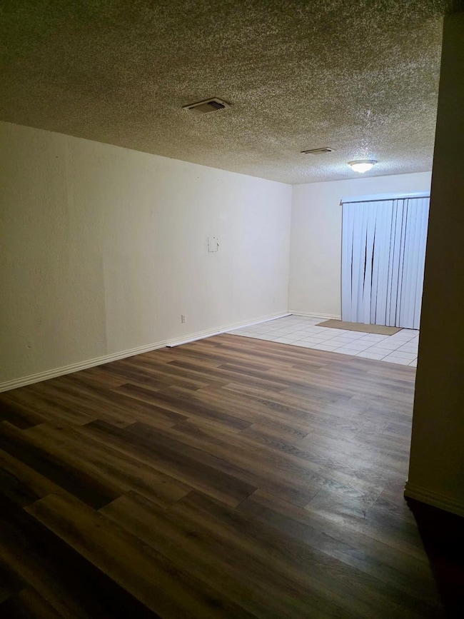 Unfurnished room with visible vents, a textured ce