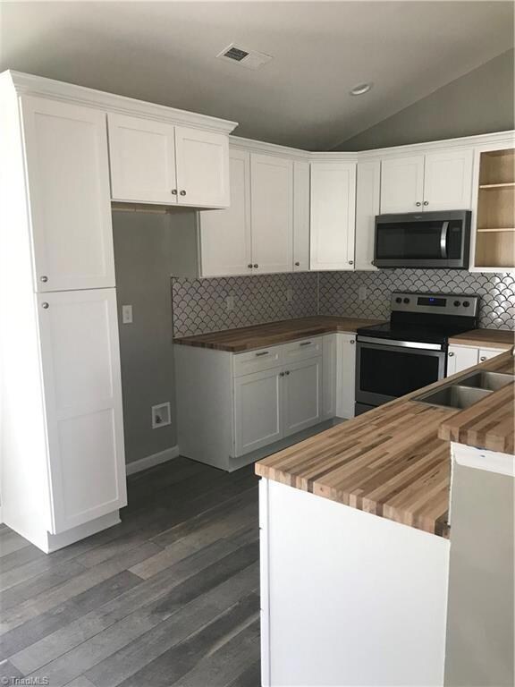 NEW:  white shaker style cabinets, pantry, tile backsplash, butcher block counters and Stainless Steel appliances.