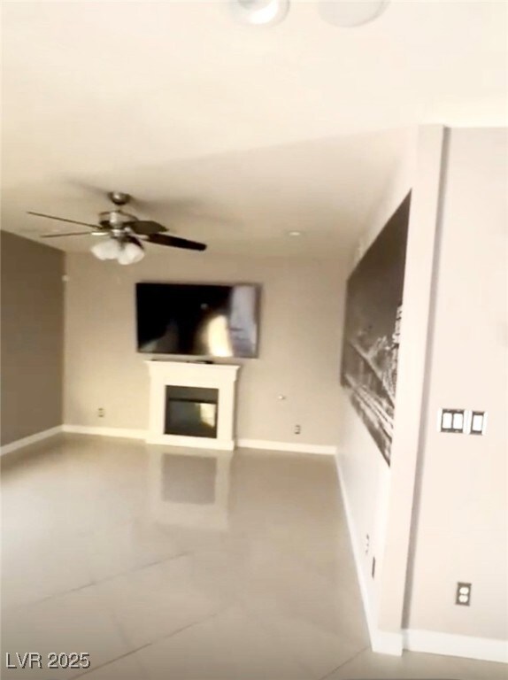 Unfurnished living room with baseboards and ceiling fan