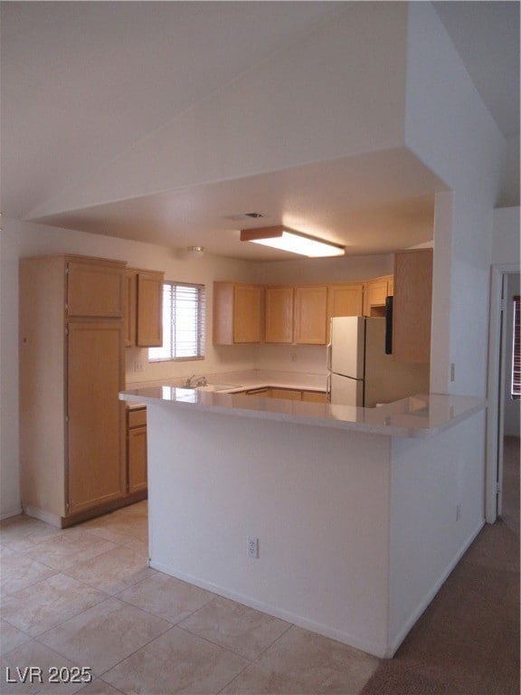 Kitchen featuring a peninsula, refrigerator, light