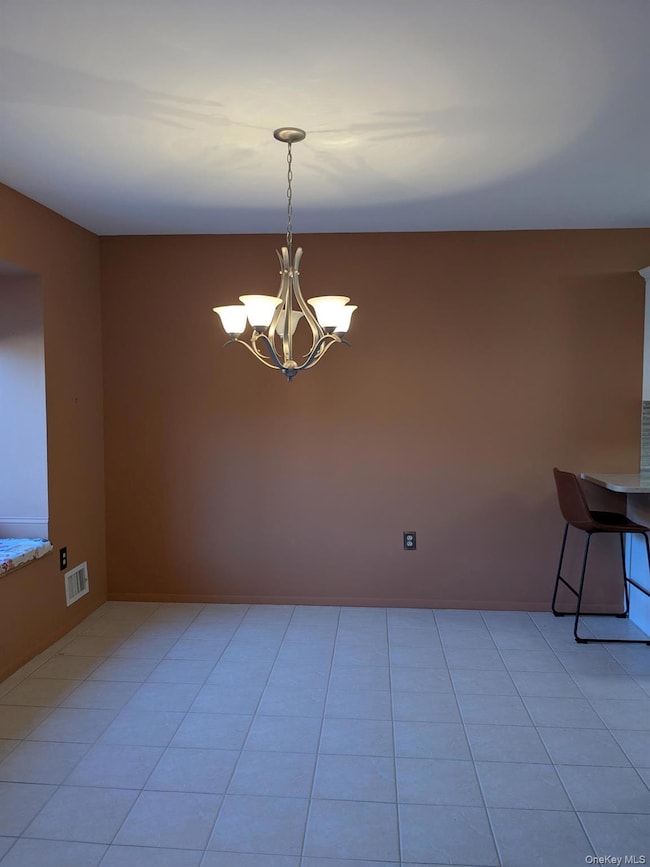 Dining Area with light tile patterned floors and a chandelier