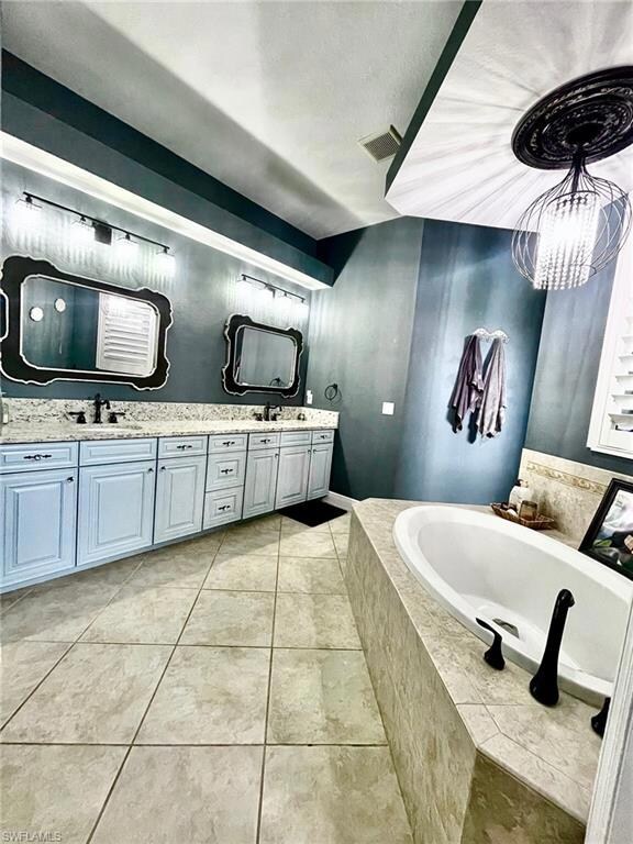 Full bathroom with a garden tub, double vanity, tile patterned floors, and a chandelier