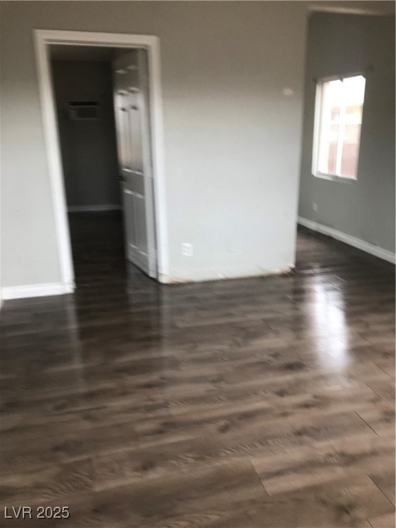 Unfurnished room featuring baseboards and dark wood-style flooring