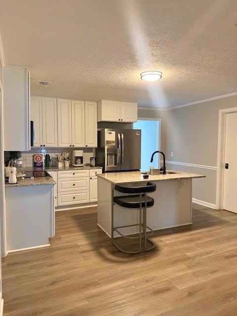 Kitchen featuring stainless steel fridge with ice dispenser, white cabinetry, a textured ceiling, a sink, and wood finished floors