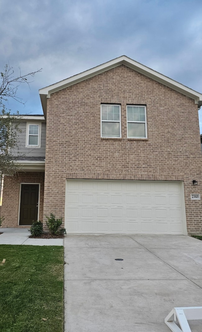 View of front facade with driveway, a garage, and brick siding