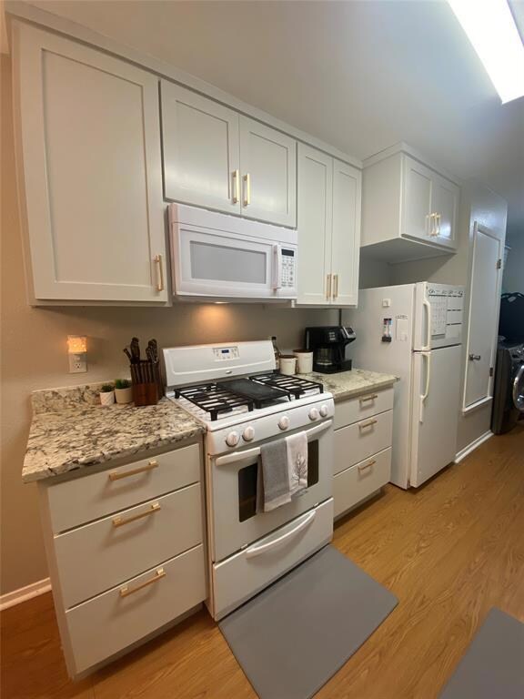 Kitchen featuring white appliances, light wood fi