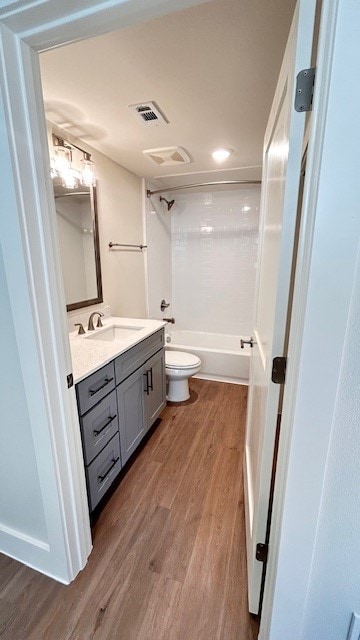 Bathroom with washtub / shower combination, vanity, and dark wood-style flooring