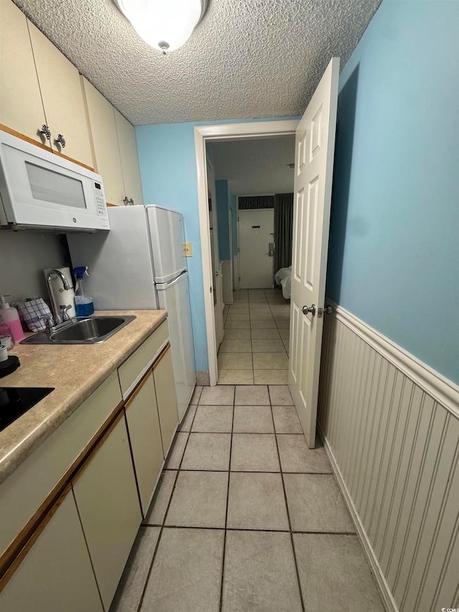 Kitchen featuring white microwave, a sink, light t